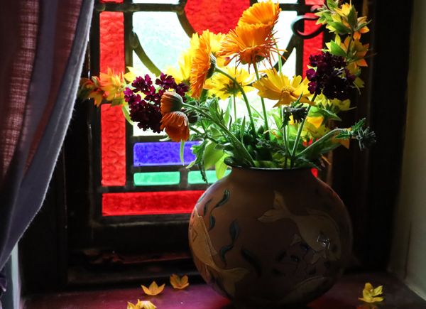 A bowl of flowers in front of a stained glass window thumbnail