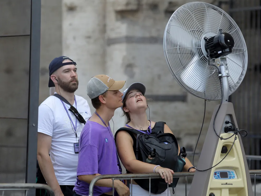 People cool off in front of an outdoor fan