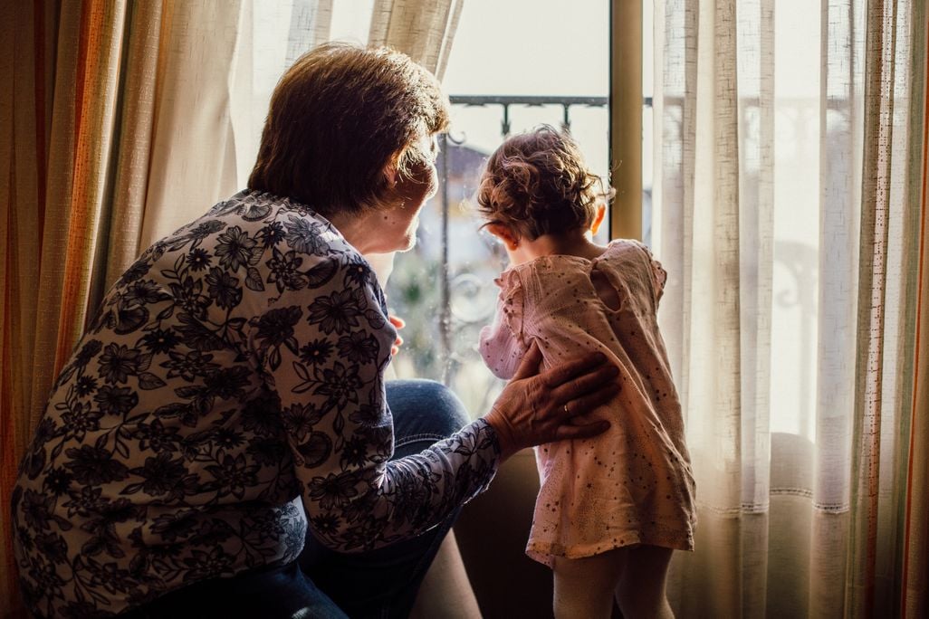 Grandmother and child looking out window