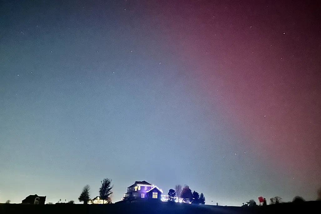 Pink aurora in the sky above a house