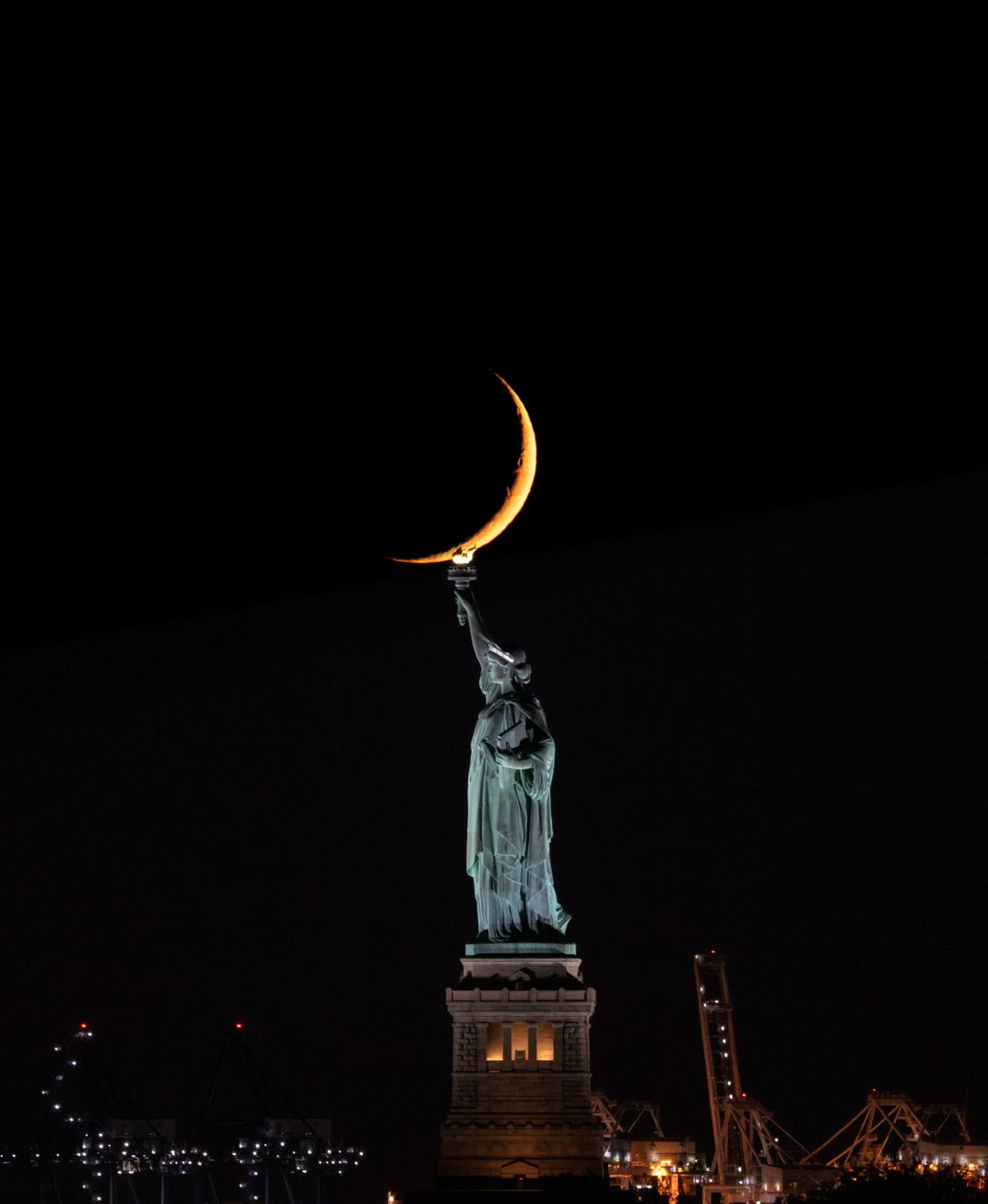 A crescent-shaped moon seemingly rests on Lady Liberty’s torch.