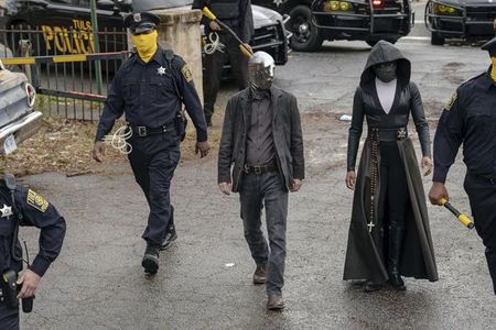 In a scene from the HBO series, Tulsa’s masked police force prepares for a raid. Detective Wade Tillman (known as “Looking Glass”) is played by Tim Blake Nelson. Detective Angela Abar (known as “Sister Night”) is played by Regina King