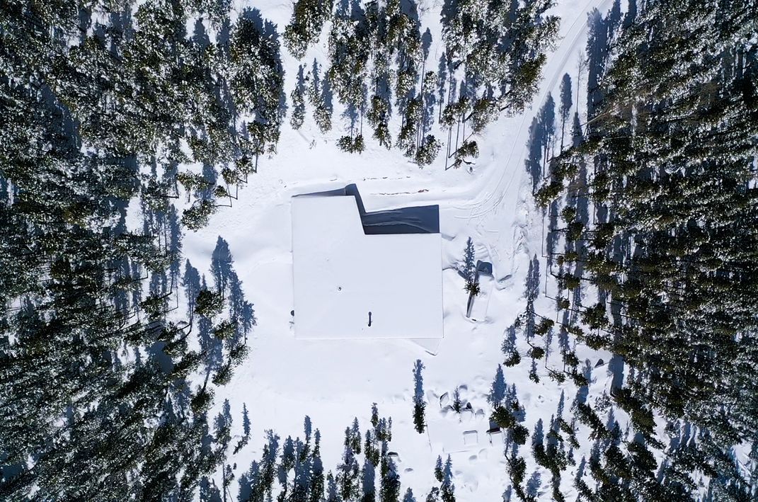 a snow covered house surrounded by a forest is shown from straight above