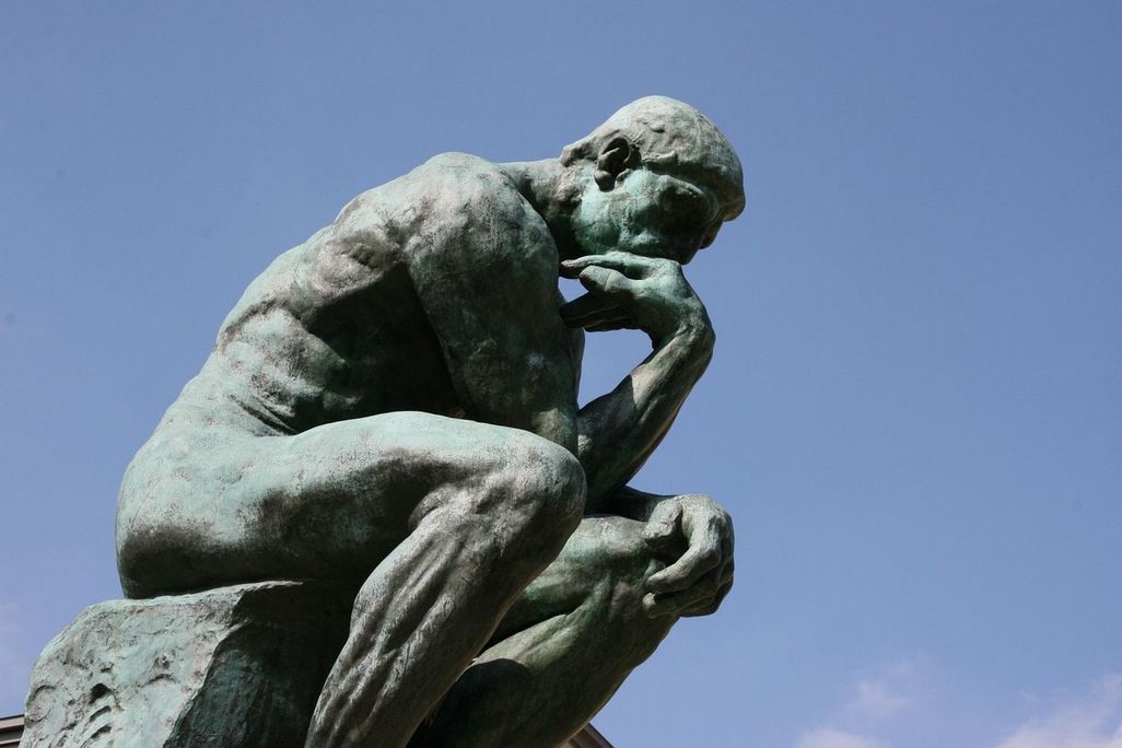 A sculpture of a man resting his chin on his hand while sitting down