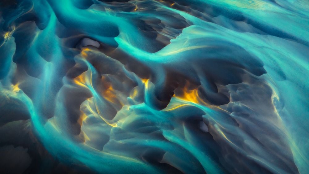 Viewed from above, this Icelandic river becomes a masterpiece of nature, its paths traced like brushstrokes on a canvas. Soft flows shift from deep blues to black where sandbanks emerge, and rare glacial particles lend an ethereal hue.