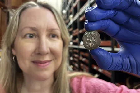 Kat Baxter, curator of archaeology and numismatics for Leeds Museums and Galleries, poses with the 2,000-year-old coin.