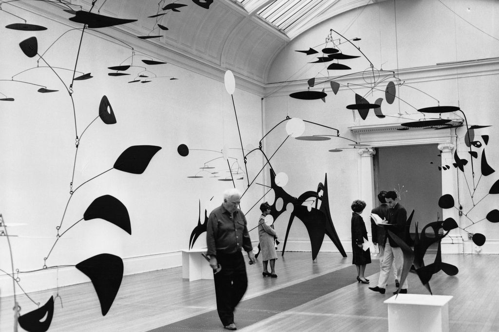 Alexander Calder checks some of his mobiles during a 1962 exhibition of his work at Tate London