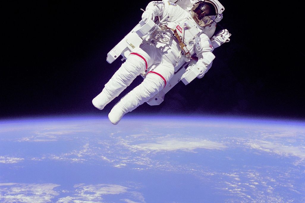 An image of Astronaut Bruce McCandless II participating in extra=vehicular activity in space. The astronaut appears to be floating out in space without being tethered to the space shuttle.