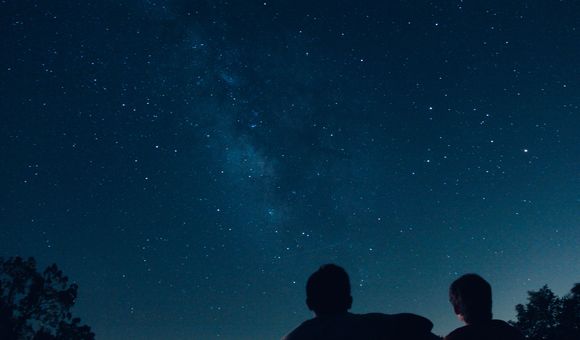 A pair of silhouetted people stargaze