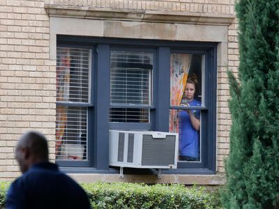 A Dallas resident in a neighborhood where one of the persons diagnosed with Ebola lives peers out of her window. 