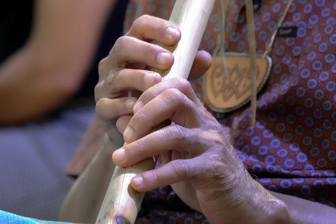 Close-up on two hands playing a wooden flute.