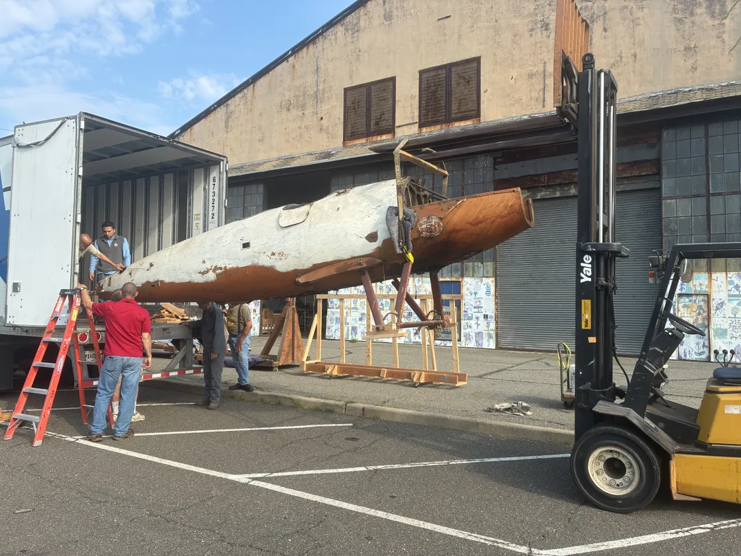 People unloading a large aircraft component from a truck