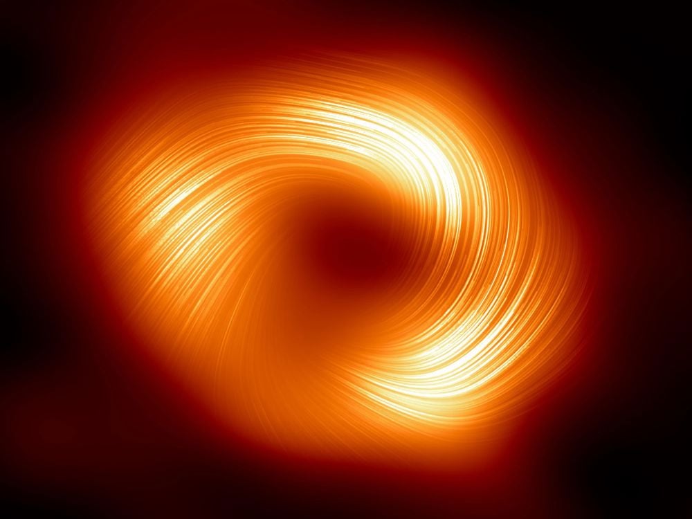 Orange light indicating magnetic fields spirals around the dark center of a black hole