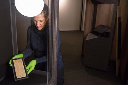 Jane Klinger, chief conservator for the United States Holocaust Memorial Museum, holds one of the cloths that Mansour Omari smuggled out of Syria.