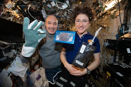 Luca Parmitano and Christina Koch with milk and a cookie.