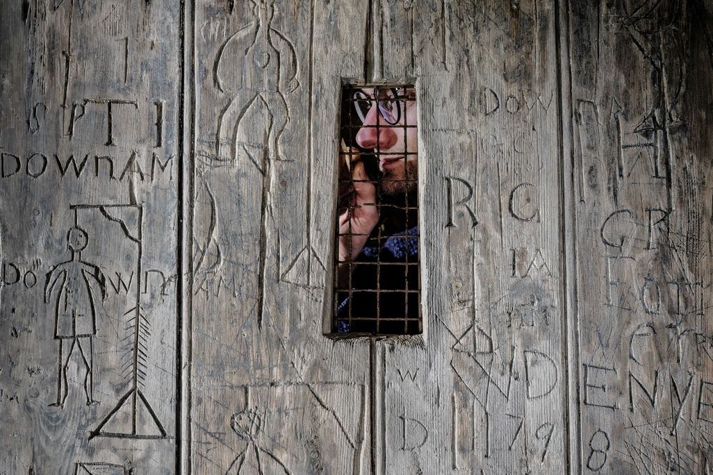 Old wooden door with a window and a man on the other side