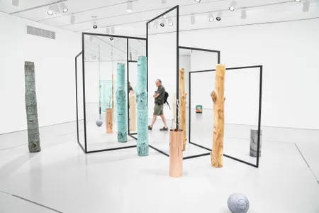 To walk within Alicja Kwade's enigmatic installation, WeltenLinie, where large metal rods frame double-sided mirrors, is like passing into some strange new dimension.