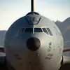 A close-up, head-on view of the nose and cockpit section of a gray U.S. Air Force KC-10 Extender aircraft parked in an aircraft boneyard, with mountains in the distant background.
