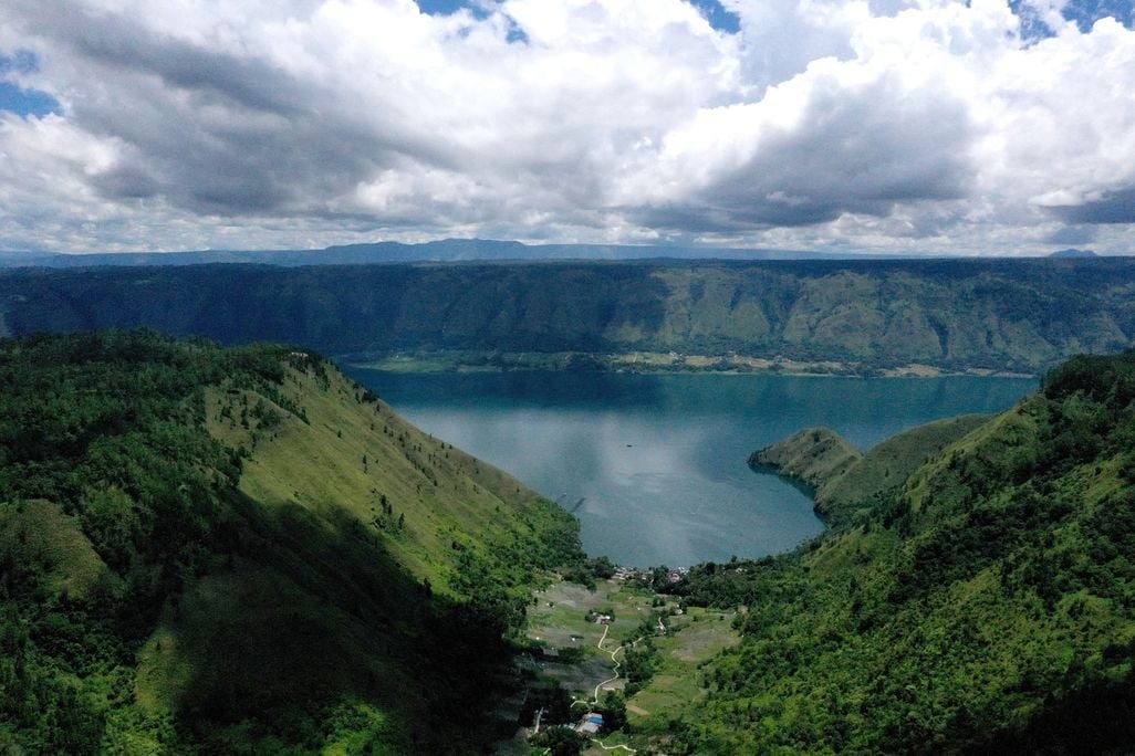 An aerial photo of a lake surrounded by green hills
