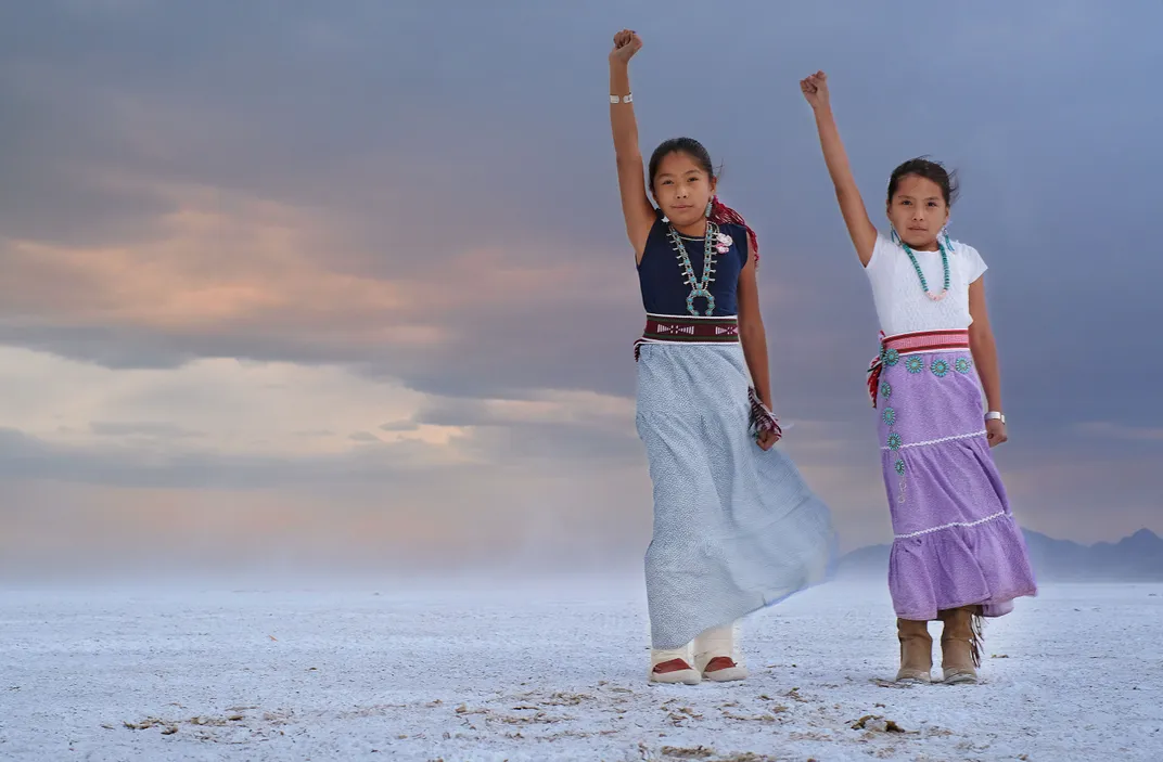 Two children stand, each with one arm raised.