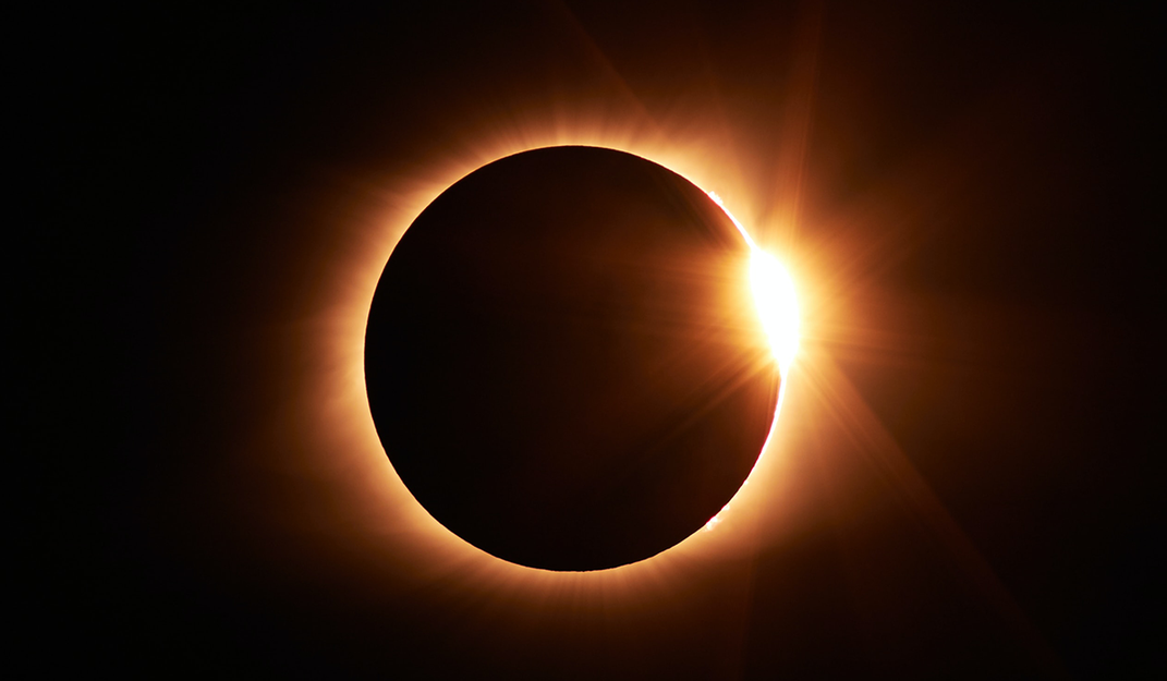 A flare ignites the sun's corona during a total eclipse.