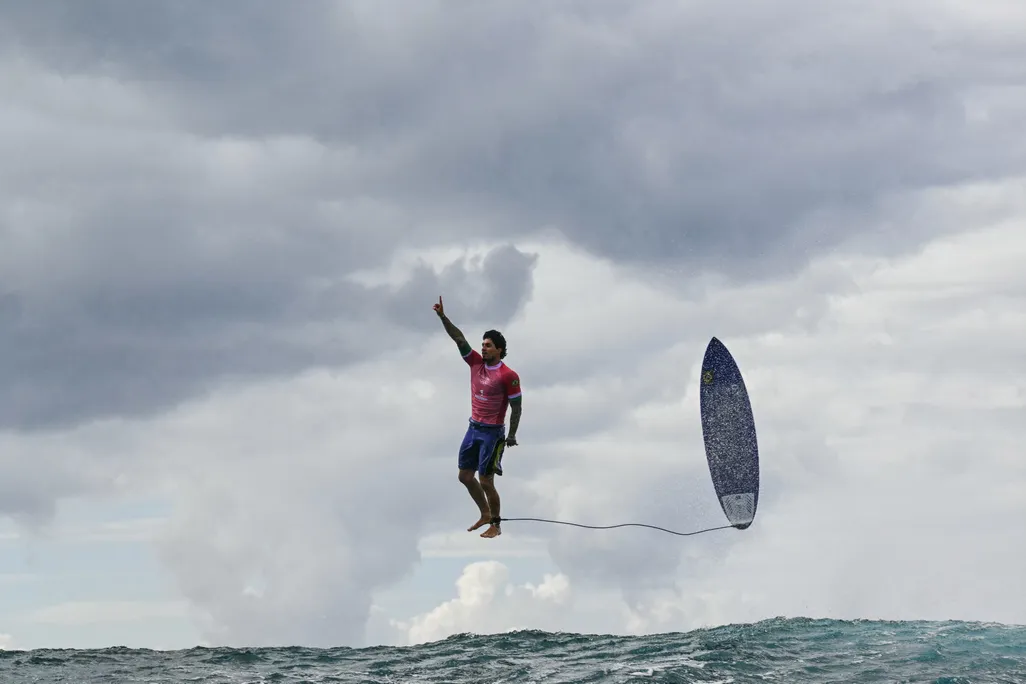 Surfer and his surfboard floating through the air above ocean water