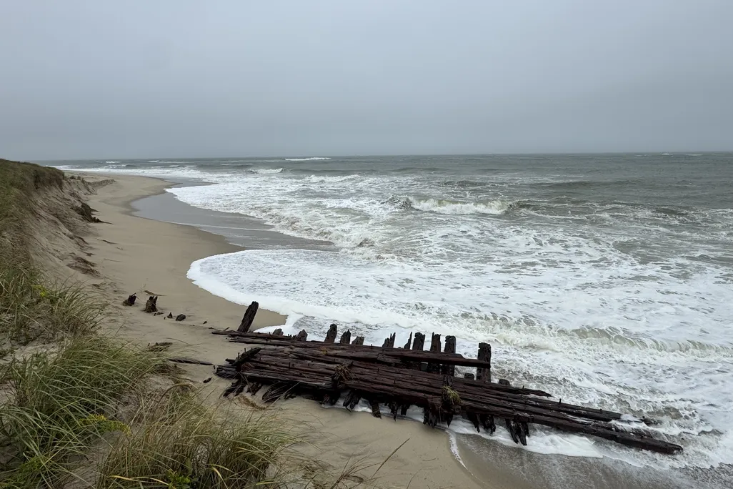 Wooden structure lying on a beach with waves lapping the shore