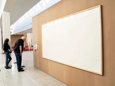 Visitors to the Kunsten Museum view Jens Haaning&#39;s Take the Money and Run&nbsp;(2021), consisting of two blank canvases.