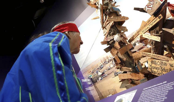 John Richard Edwards (Onondaga) takes part in the installation of the mile-marker post from the Dakota Access Pipeline in the exhibition 