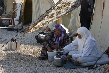 Syrian refugees cook outside a tent at the Majdal Anjar refugee camp in Bekaa Valley near the Syrian border in eastern Lebanon, September 9, 2013.