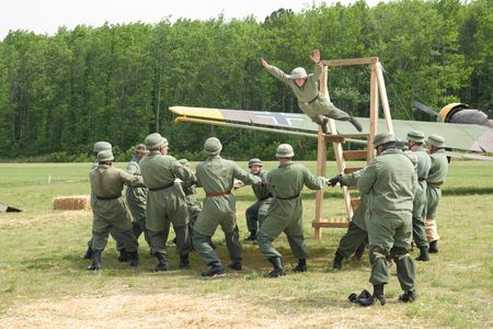 At the airshow, re-enactors help create the illusion of wartime Europe. Near a Junkers Ju 52, some pose as German paratroopers practicing aircraft exit techniques.