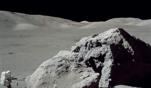 Jack Schmitt picking up the gnomon after collecting samples. This view is to the west toward the Lee Lincoln Scarp. Apollo image AS17-140-21496.