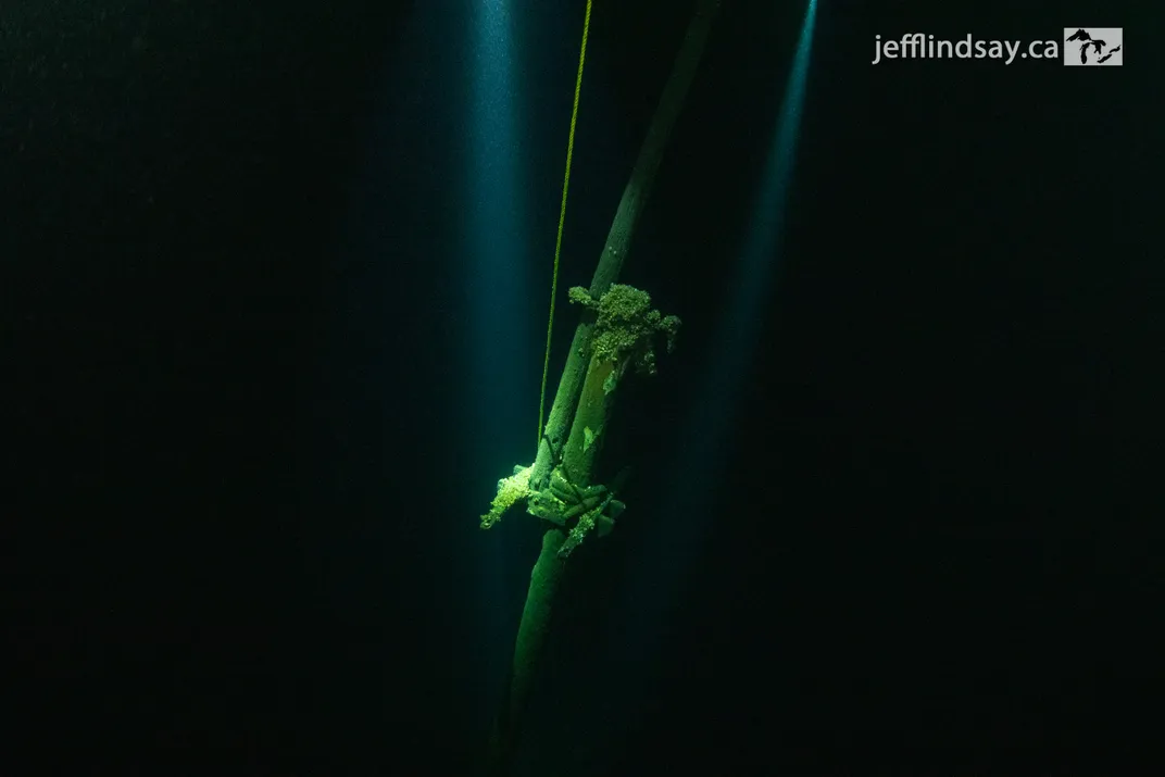 Underwater view of part of a shipwreck against a mostly black background