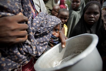 A malnourished Somalian baby is held by its mother while waiting for food during a 2011 drought.