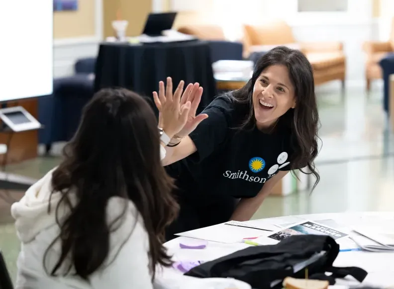 Woman with Smithsonian shirt gives girl a high five