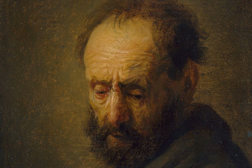 A yellow-toned, dark portrait of a white man from the chest up; his forehead wrinkles are prominent; he turns toward the viewer and wears a dark cloak, with balding, scraggly brown hair and beard, looks despondently downward