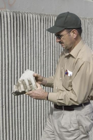 Man in baseball cap holding a baseball glove-sized chunk of concrete 