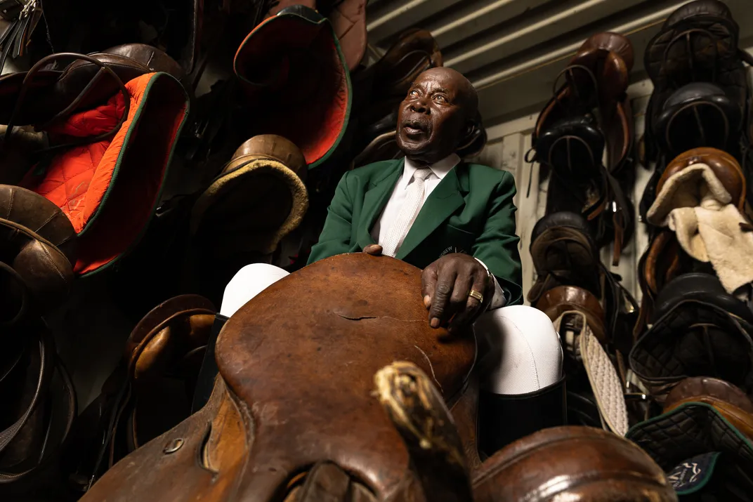 Enos Mafokate, one of South Africa’s first Black show jumpers, sits in the tack room (a repurposed shipping container) at the equestrian center he founded in the township of Soweto.