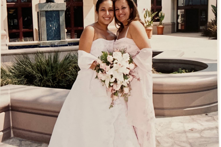 Quinceañera (fifteen-year-old girl) wearing a long strapless dress and posing by her mother's side.