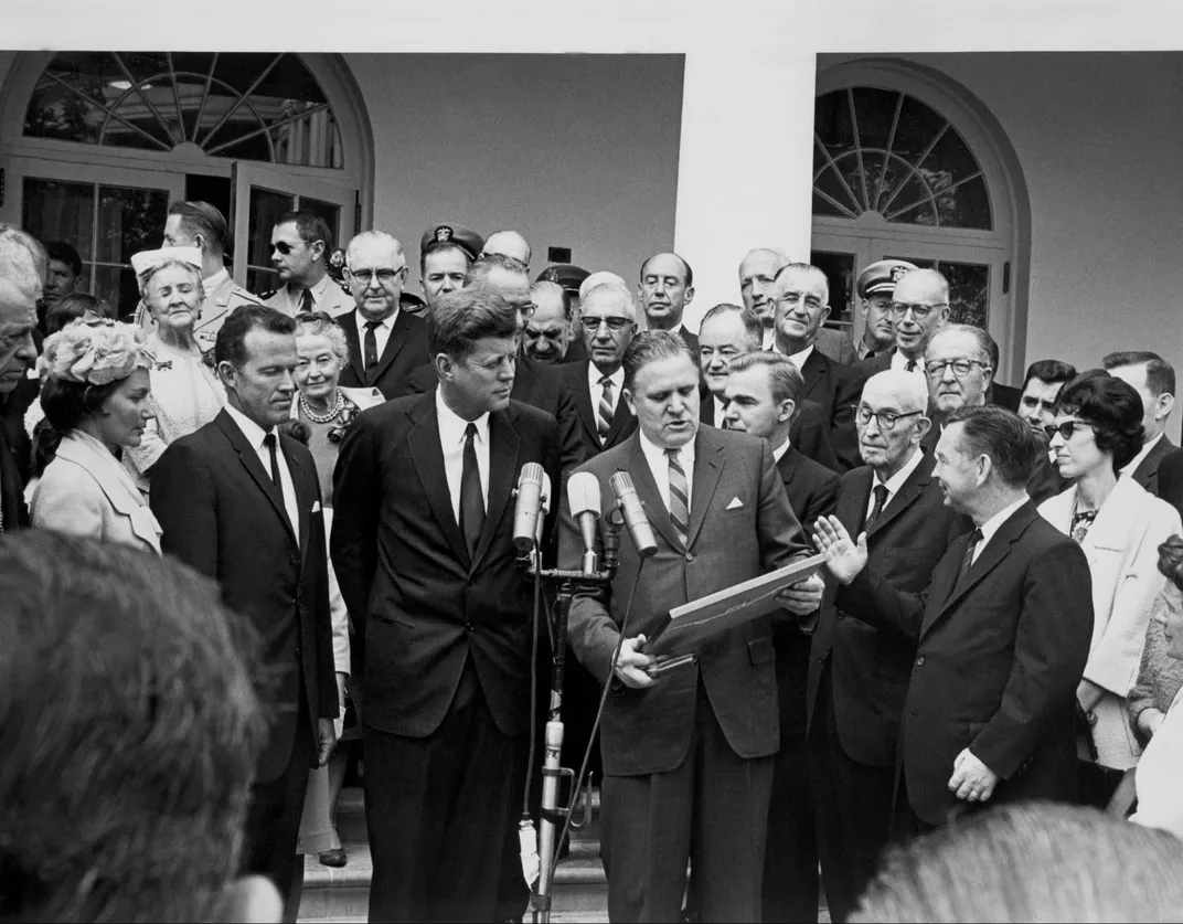 Black and white photo of crowd of people including James Webb receiving a plaque from President Kennedy in Washington DC