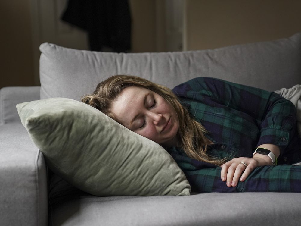 a woman lies on her side on a couch, resting on a pillow