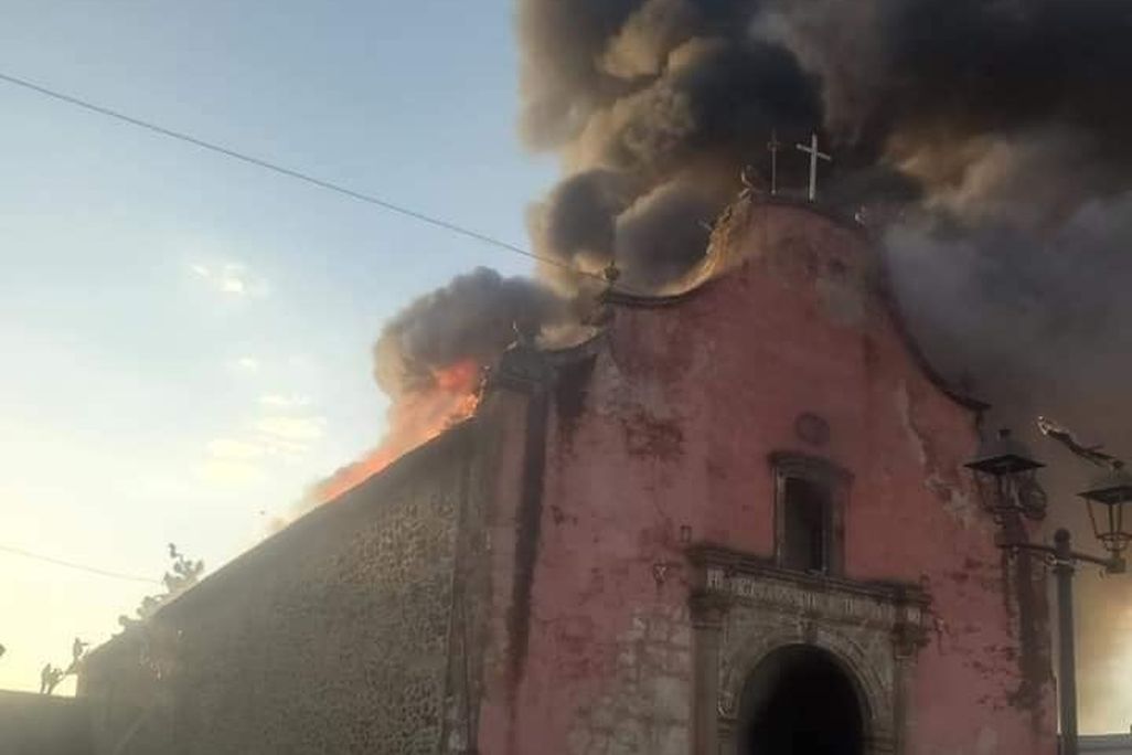 Huge clouds of dark smoke billow from the top of the old, sixteenth-century church