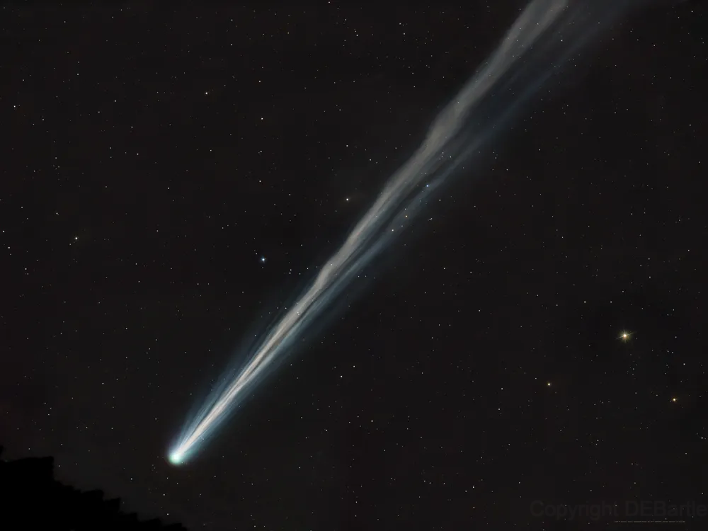 A white comet streaks across dark space