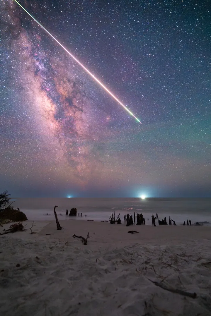the milky way and a shooting star over sand