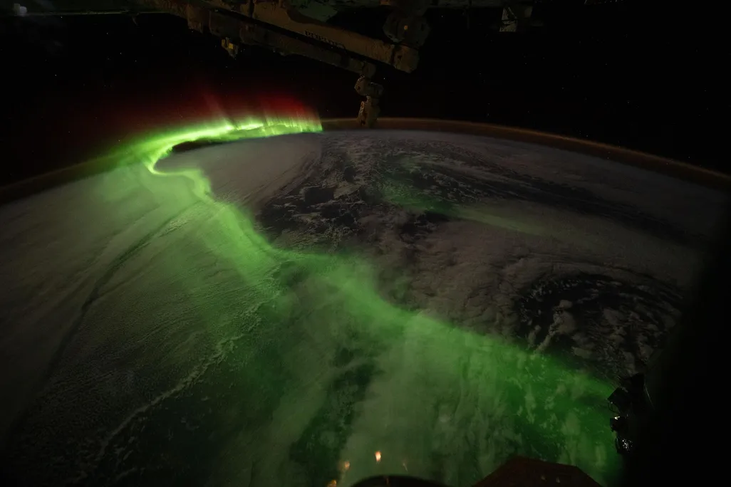 A glowing green trail curves above the Earth