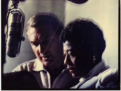 Norman Granz and Ella Fitzgerald at a microphone, 1950.