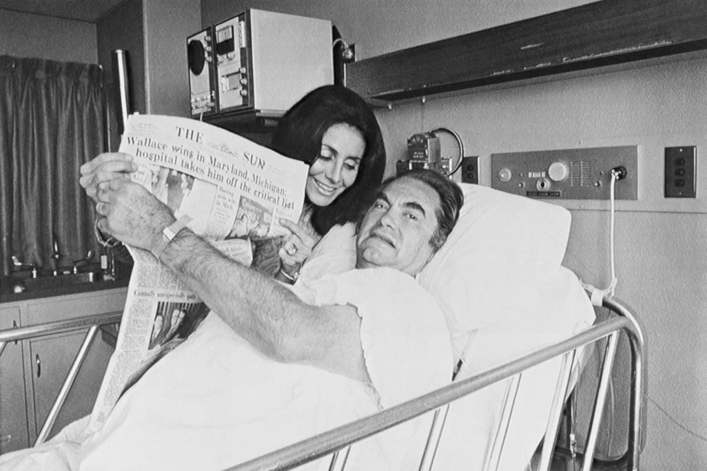 After his shooting, a hospitalized Wallace holds up a newspaper touting his victories in the Maryland and Michigan Democratic presidential primaries.