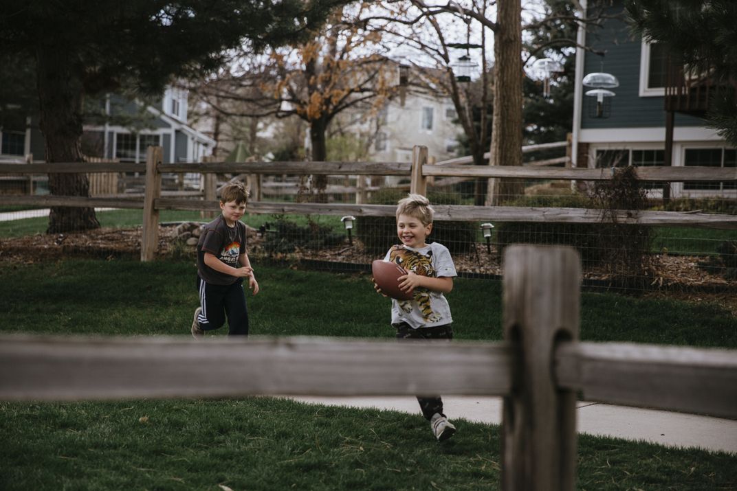 kids play with a football in a yard