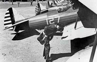 Man wearing a parachutes next to a plane during WWII.