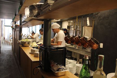 Gastromotiva student Luis Freire (right) preps plums at Refettorio Gastromotiva, with the dining room in the background.